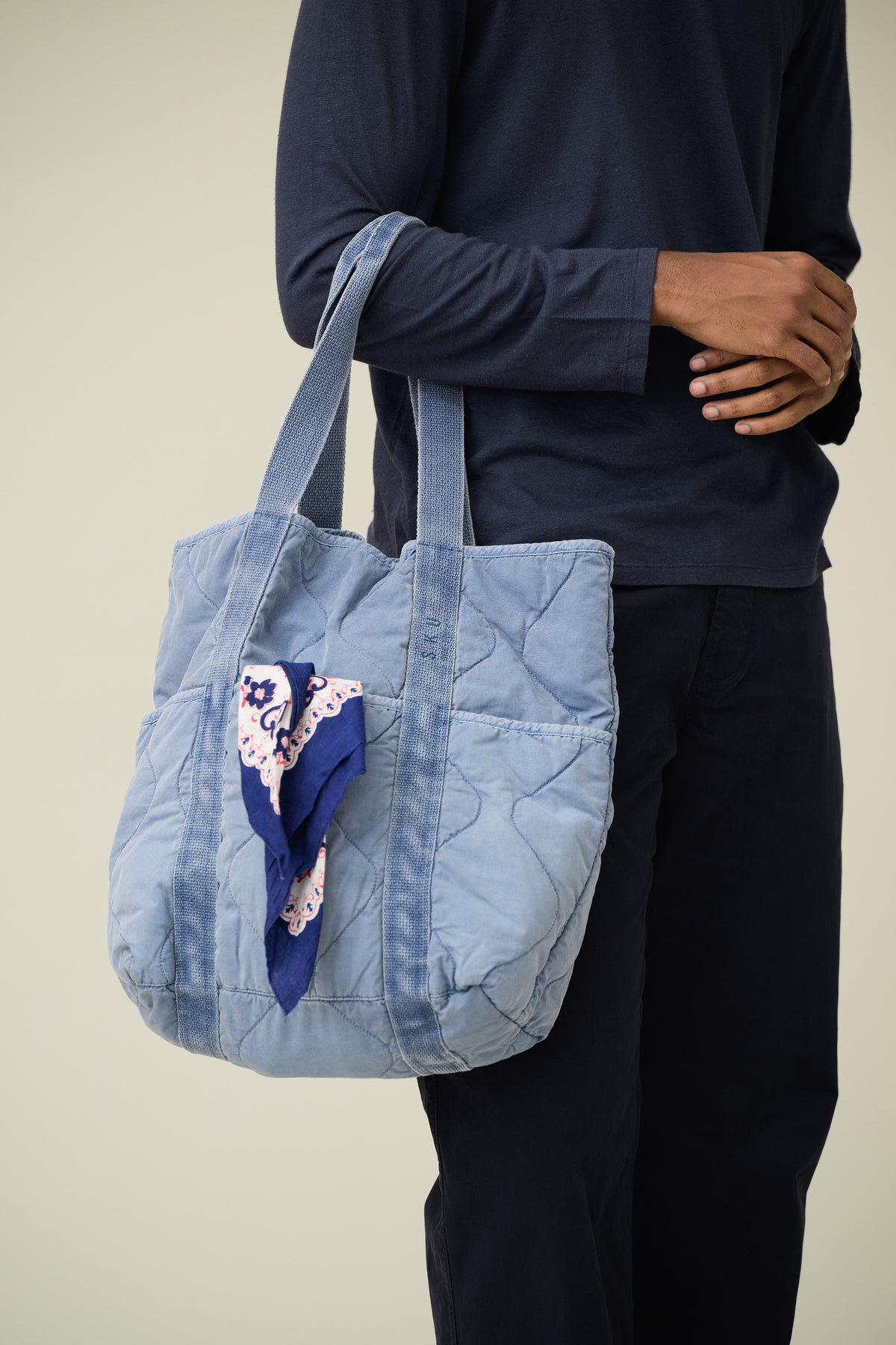 Quilted blue tote bag with top handles and side pocket with patterned patch
