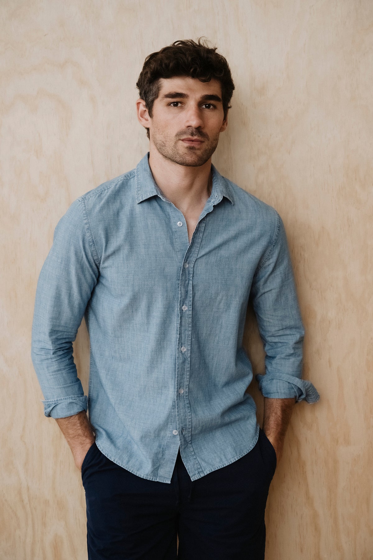 Light blue chambray button-up shirt on model, button front and long sleeves