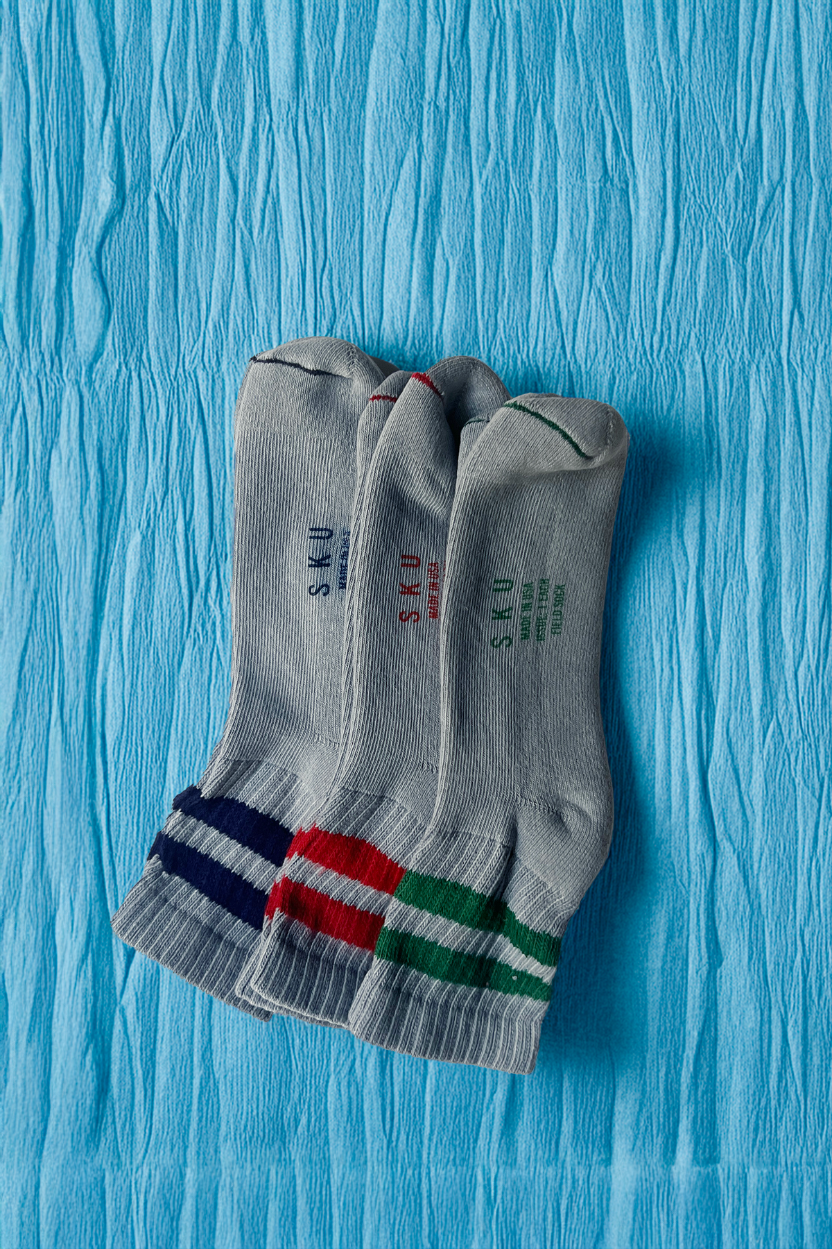 Crew socks in medium gray with ribbed cuffs and navy, red, and green stripe band