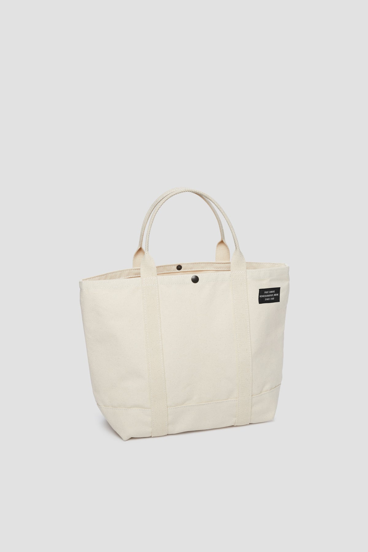 Natural canvas tote bag with long handles and small front pocket detail