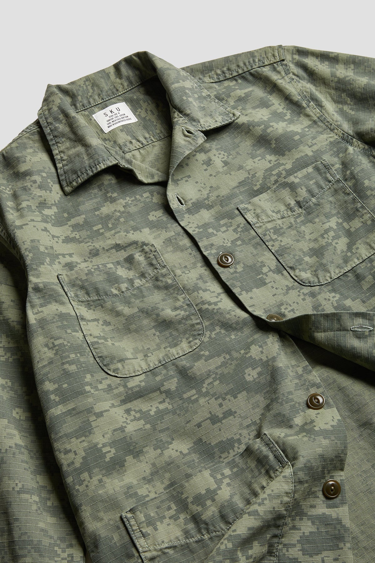Close-up of green camouflage shirt jacket with point collar and button placket