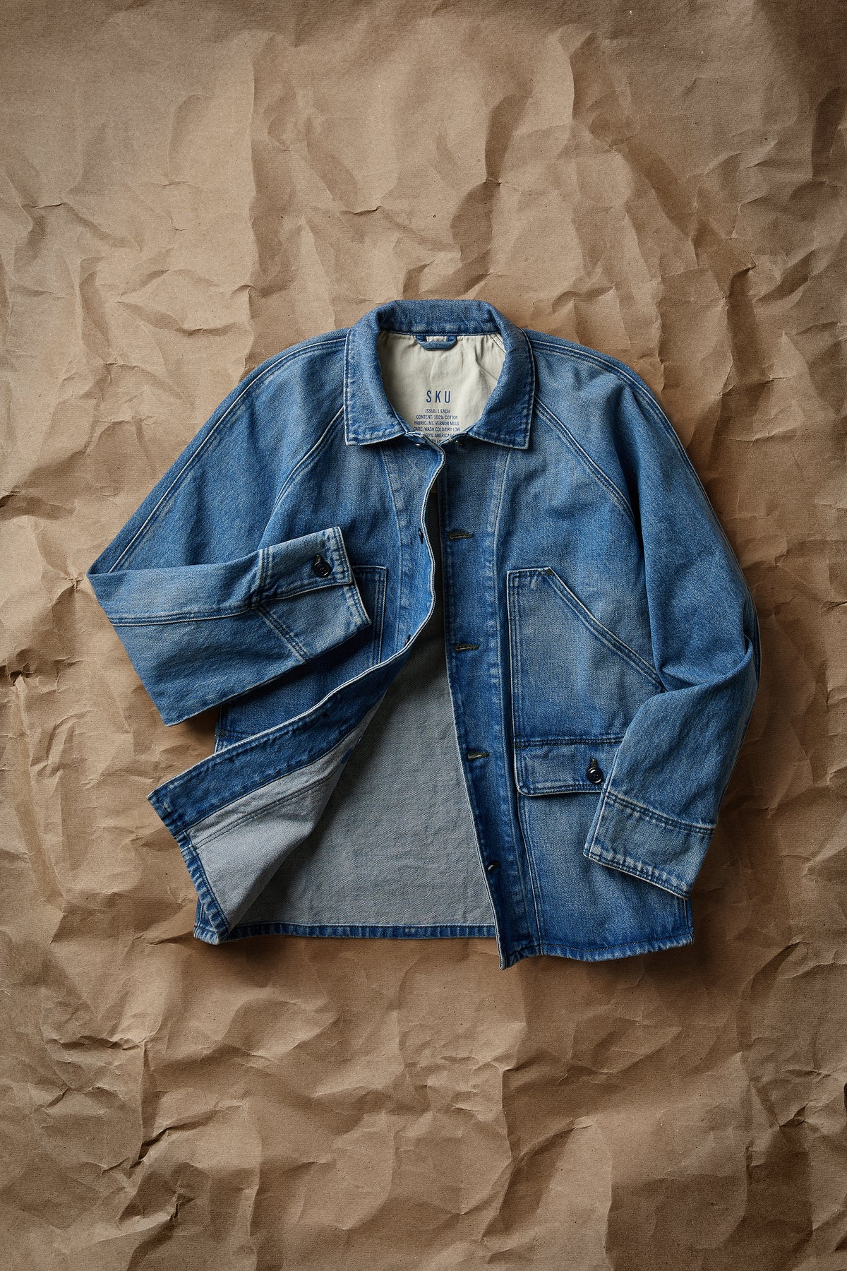 Blue denim chore jacket folded flat with button front and chest pockets