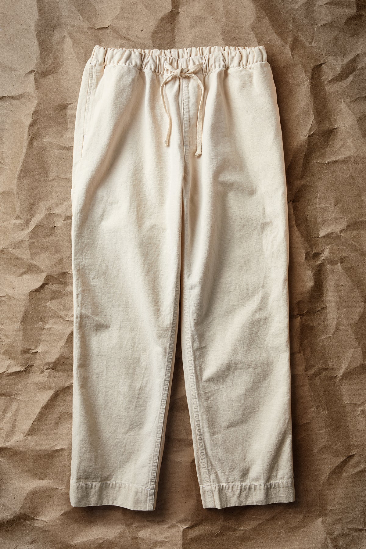 Worker pants in natural off-white cotton twill, elastic waist and drawstring, tapered leg