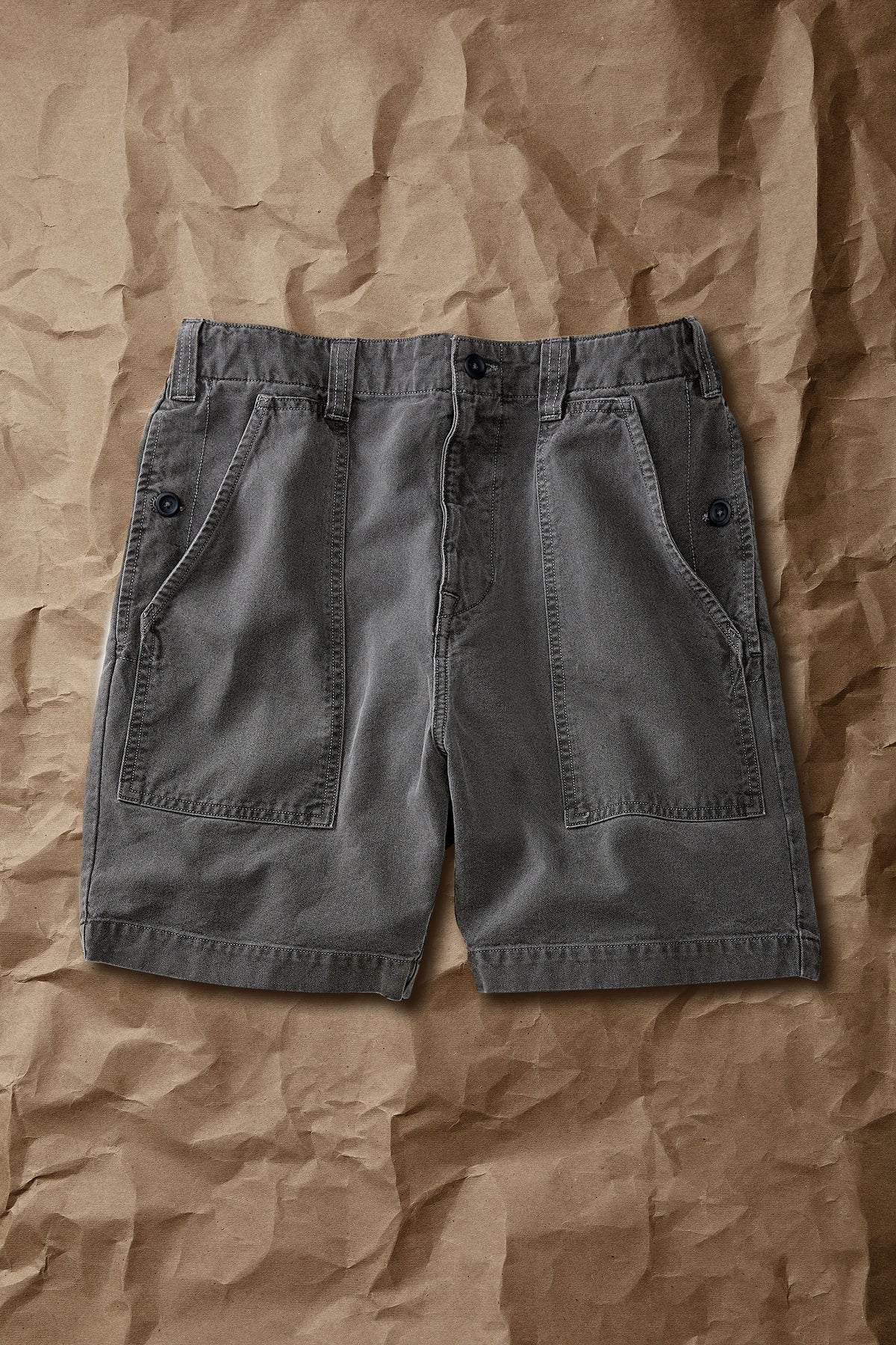 Faded black cotton drill shorts, mid-thigh length, cargo pockets, button fly