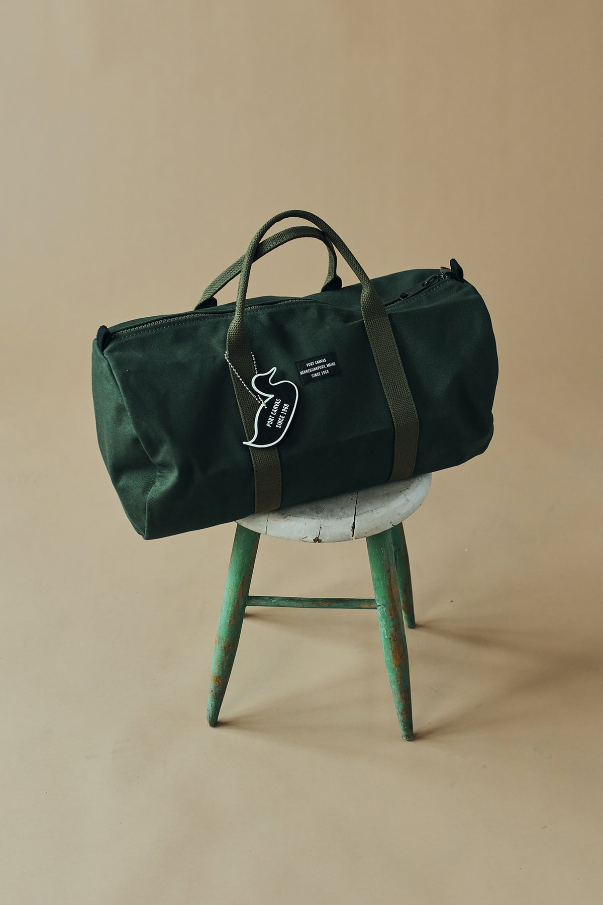 Hunter green duffel bag with white-striped handles and side logo patch