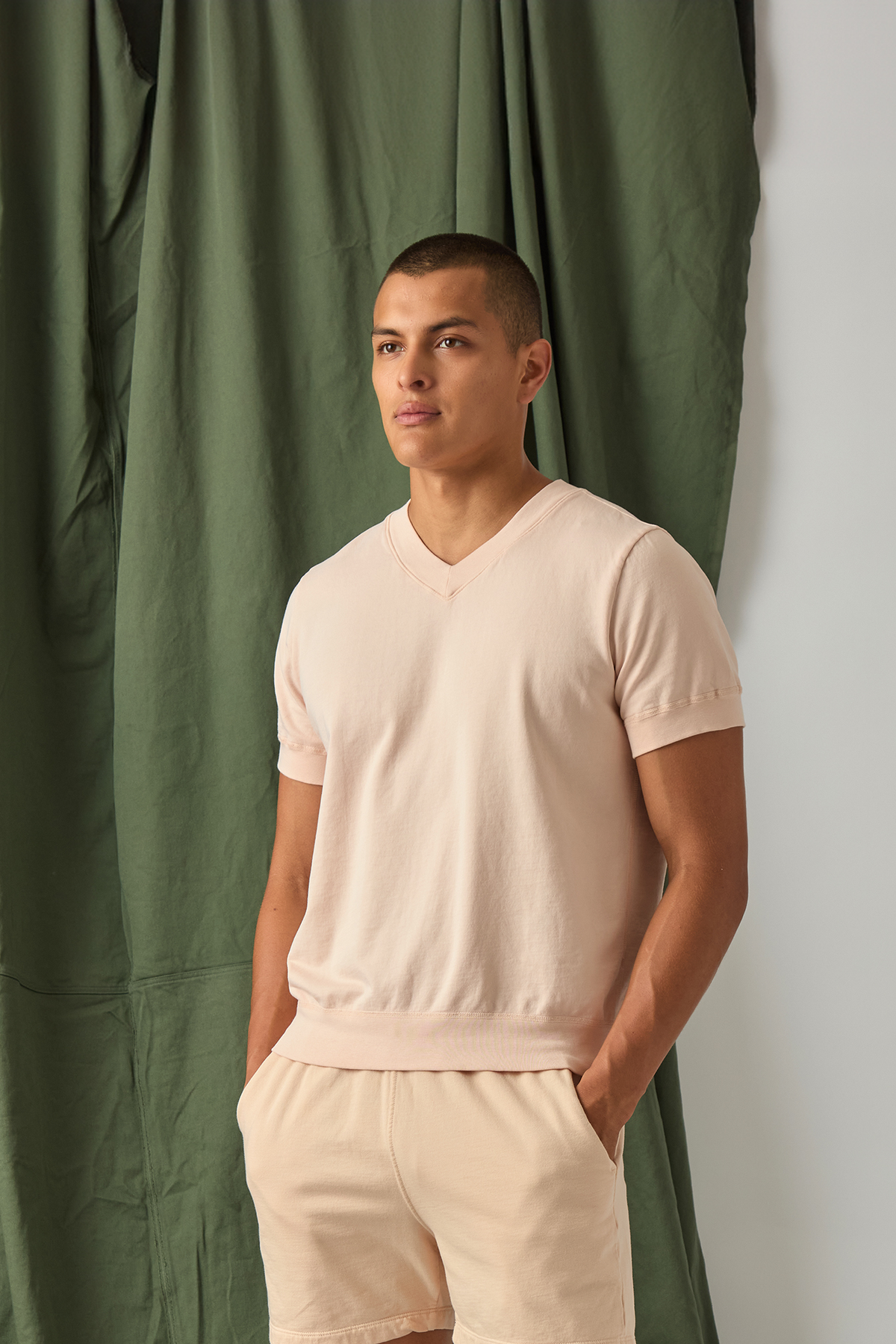 Light pink V-neck sweatshirt on model, short sleeves, ribbed hem