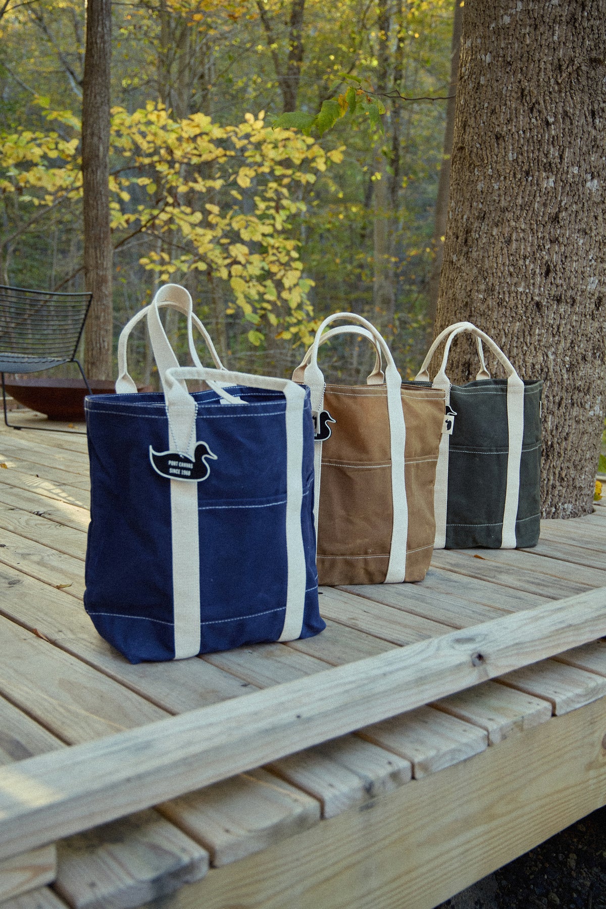 Set of double utility wax totes in navy and tan with white strap panels, outdoors.