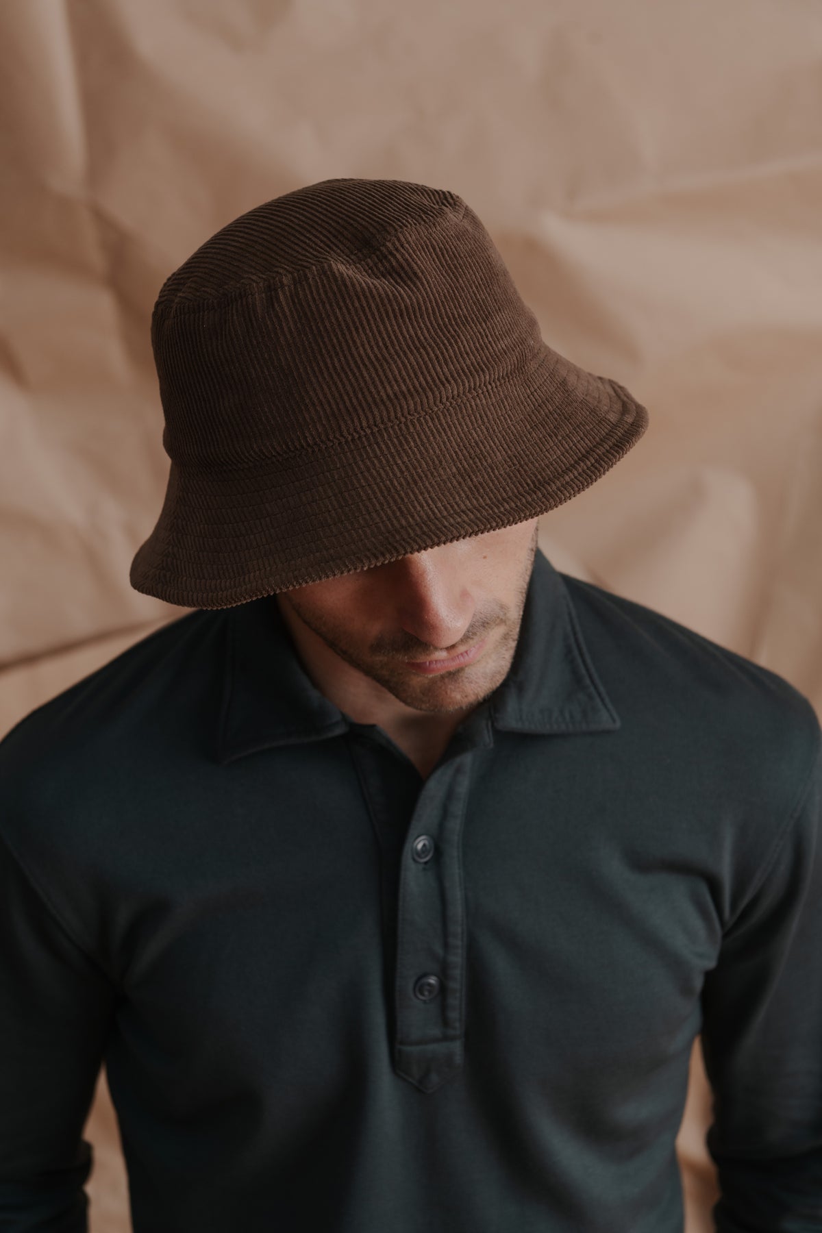 Brown wide-wale bucket hat worn by a man, brim tilted down.