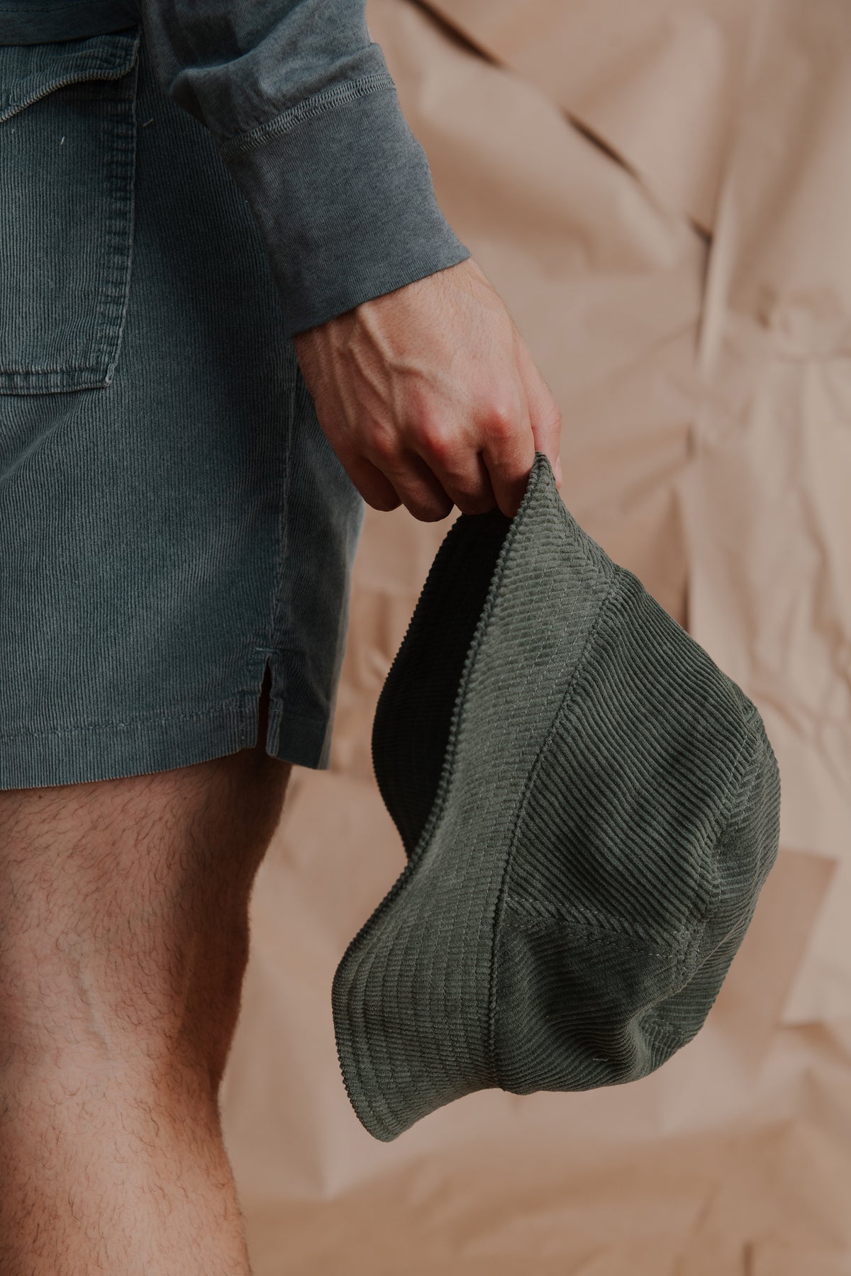 Dark green ribbed wide-wale bucket hat held in hands, brim visible.