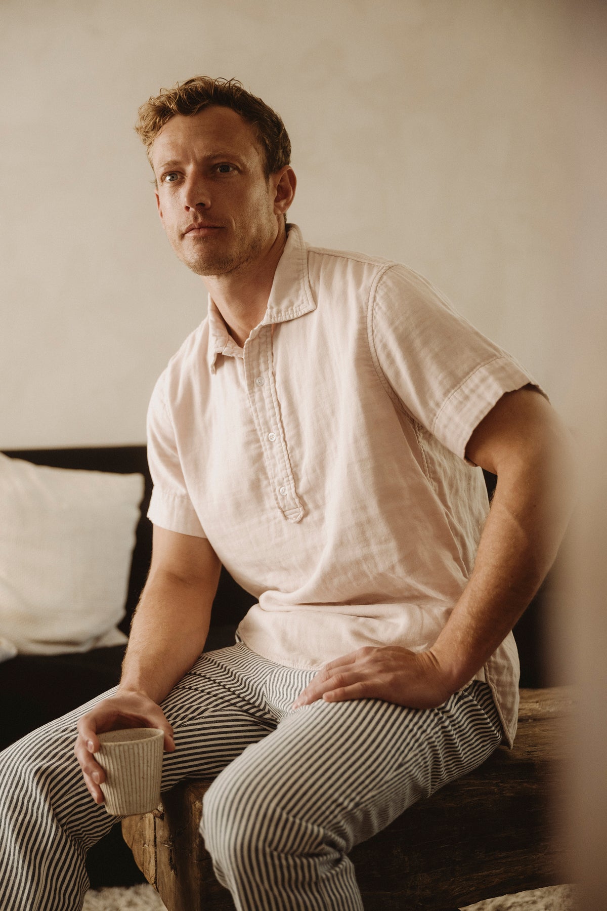 Men's white short-sleeve popover shirt worn by model, button placket and collar.