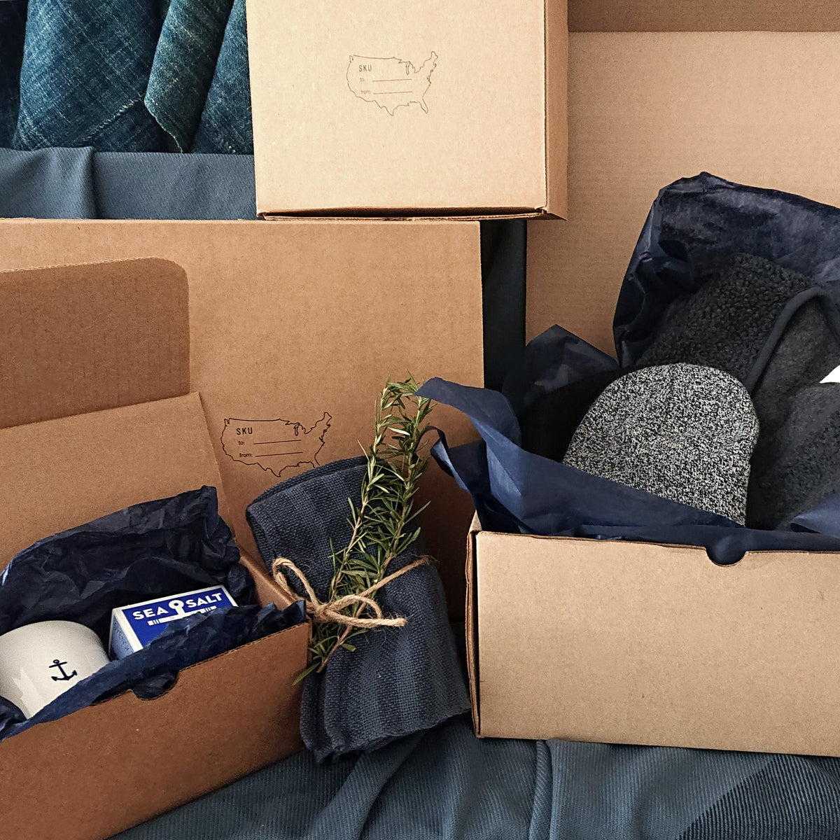 Assorted kraft gift wrap boxes with blue tissue, ribbon, and twine