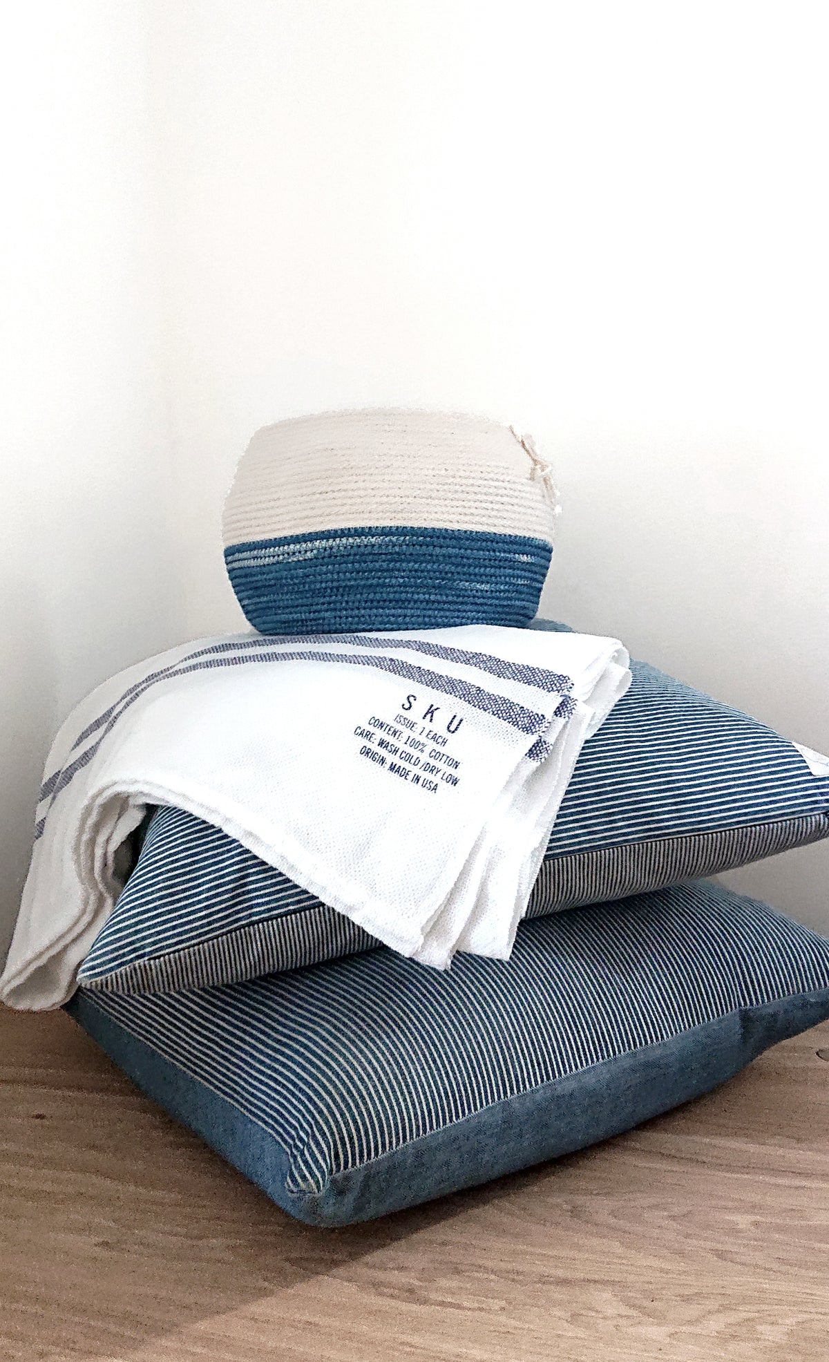 Hand-dipped basket with indigo-dipped blue base sitting on folded blue striped linens